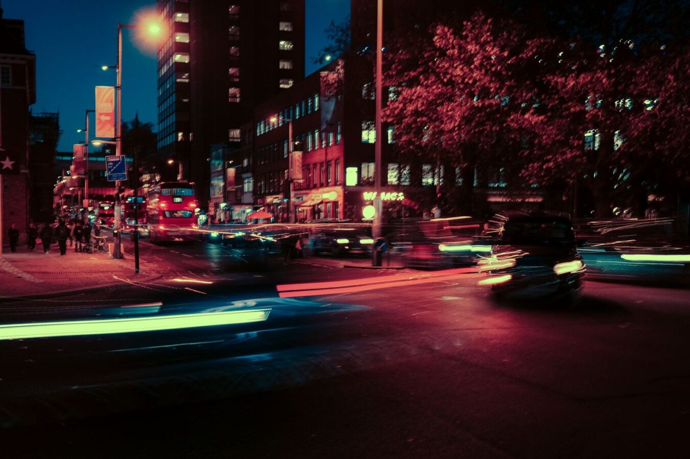 Una calle de ciudad de noche, con luces de autos en movimiento