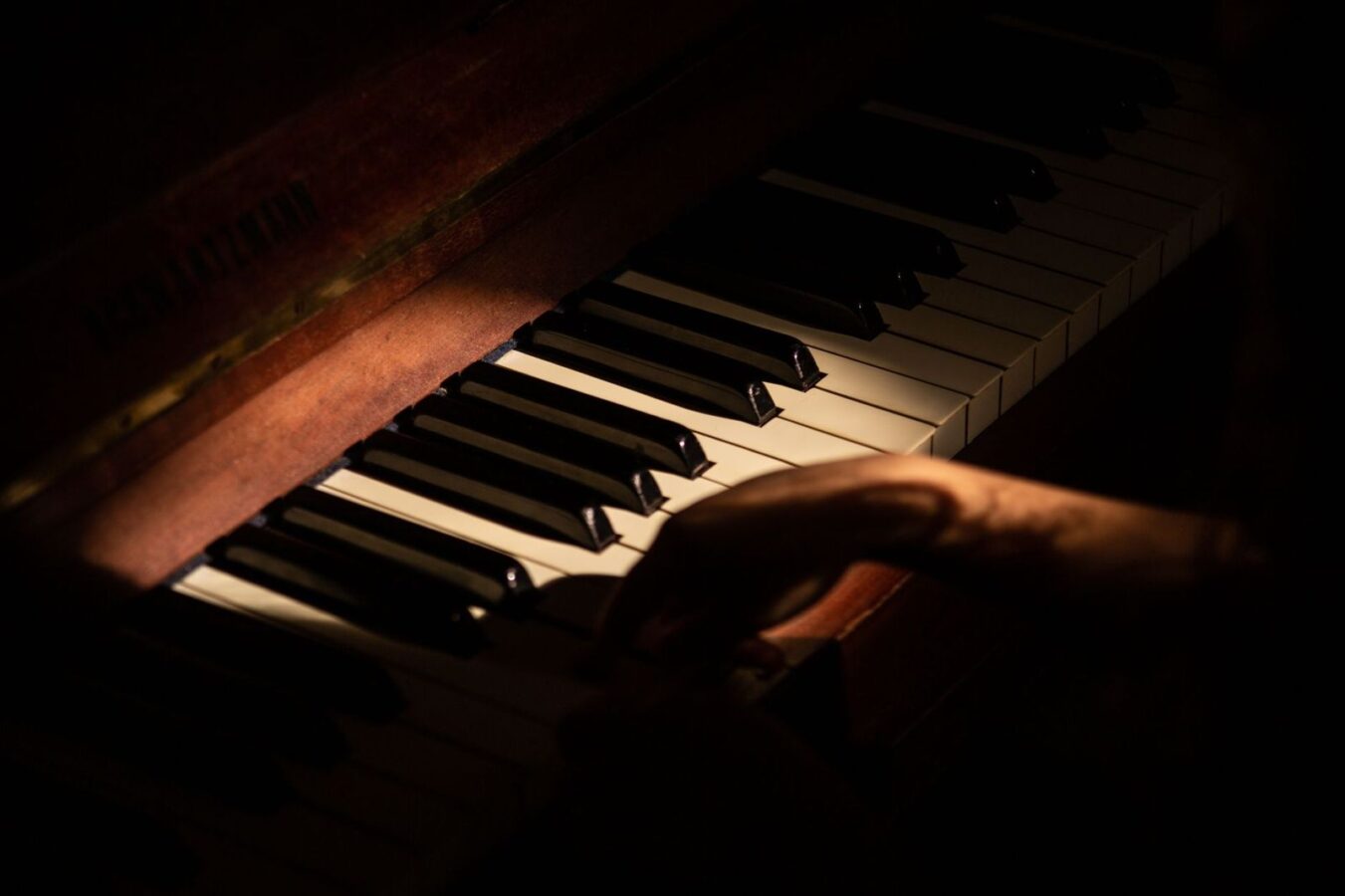 Una mano sobre las teclas de un piano, con luz cálida