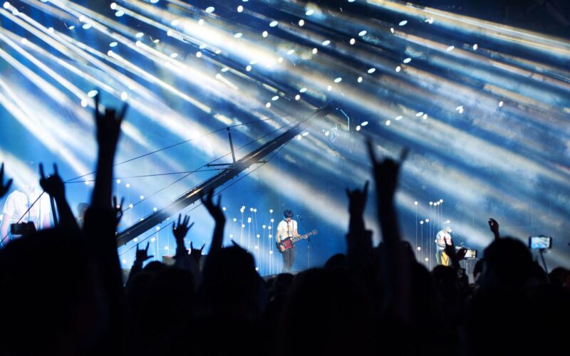 Crowd with hands raised in front of an illuminated stage
