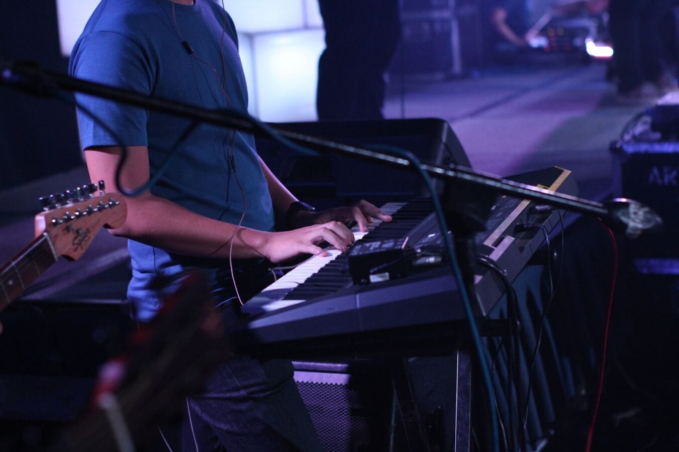 Tecladista tocando em um palco com luzes roxas