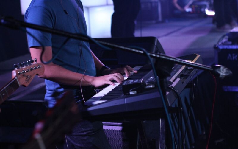 Tecladista tocando em um palco com luzes roxas
