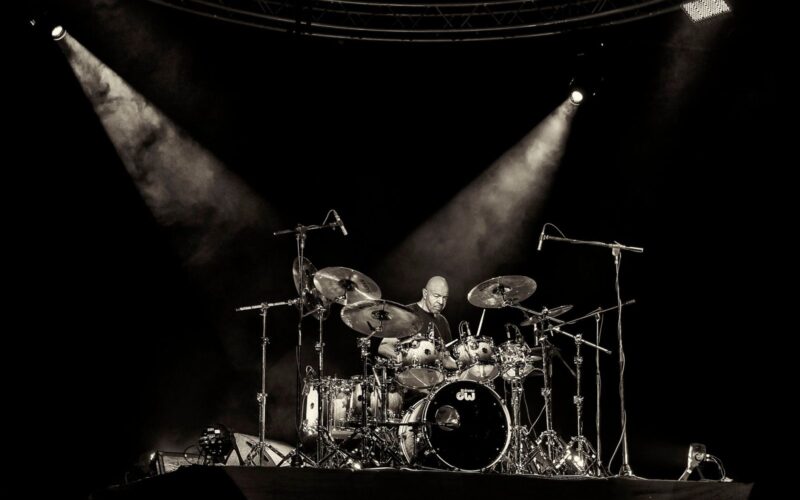 Drummer playing under two spotlights on a dark stage